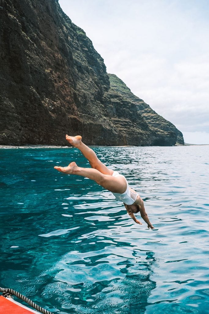 Girl Diving into Ocean with Kauai's Na Pali Coast in background